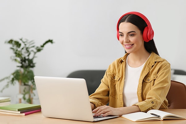 A woman with headphones on sat working on a laptop