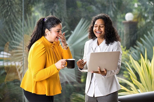 Two colleagues laughing together at a laptop